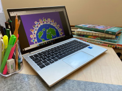 Tietokone, värikynät ja oppikirjat pöydällä