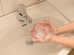 Lapsi saippuoi käsiään. A child is washing hands.